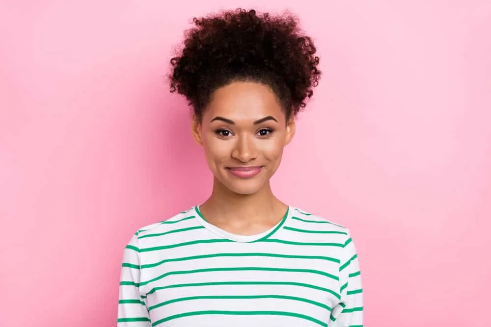 A young millennial wearing natural makeup and 4A curls colored with hair chalks.