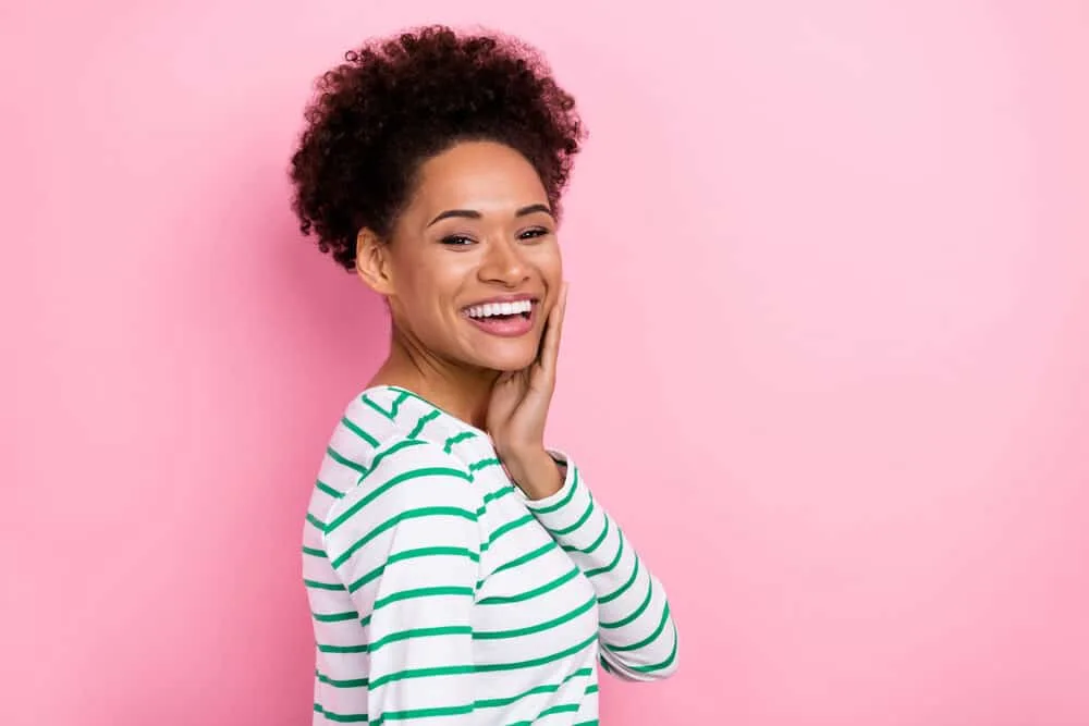 An attractive girl with hair porosity issues on 4A curls wearing pink lipsticks and freshly arched eyebrows.