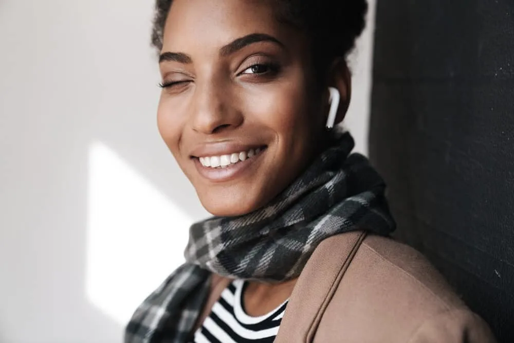 Black woman with naturally curly 4A hair strands winking with her right eye.