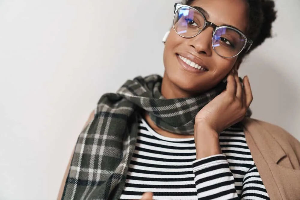 Lady wearing a black and white shirt, eyeglasses, and a white scarf to stay warm