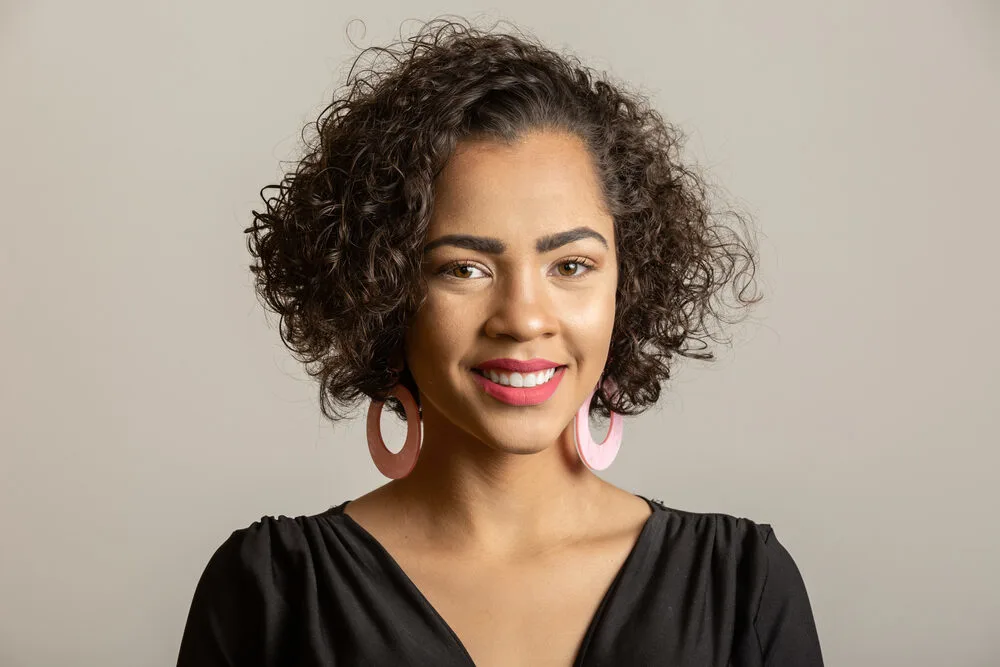 Cute black girl with a great smile wearing natural curls styled with a hair rinse from the "miracle tree".