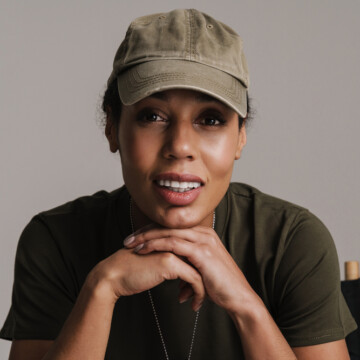 A black female soldier in uniform with naturally curly long hair wearing a ponytail that aligns with grooming standards.