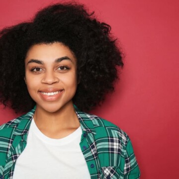 A cute African American woman with 4A curls treated with henna hair dye wearing a casual white t-shirt.