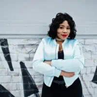 Stylish African American woman with an oval face shape and short hair length wearing a blue jacket.