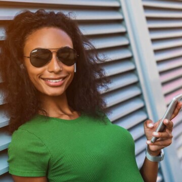 Beautiful African American female with curly natural hair wearing straight hair while using her iPhone.