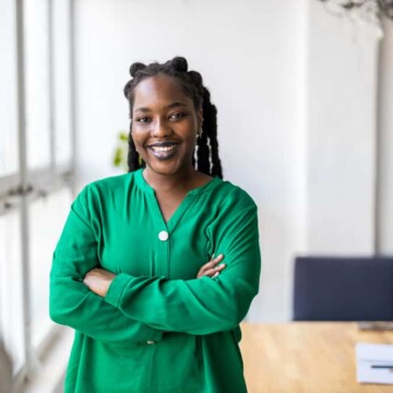 African American female with healthy dreads styled with hair accessories and natural oils wearing a green shirt.