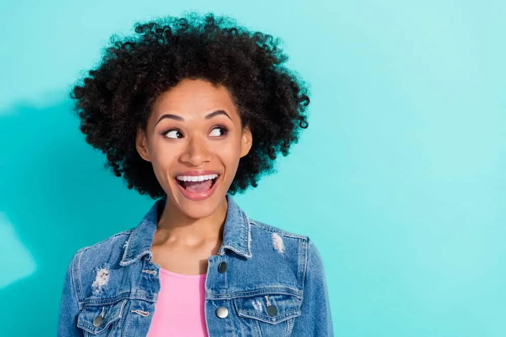 African American female with curly hair strands with brown semi-permanent hair dye to add highlights.