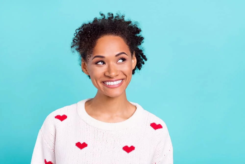 Attractive black female with metallic dyes on bouncy 4B curls looking curious with a cute smile.