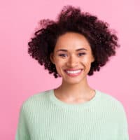 Cute African American female with 3B dark brown hair wearing a light green sweater.