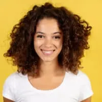 Cute African American female wearing Splat hair dye from a professional colorist on dark brown curls.