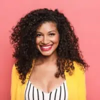 Beautiful African American female with naturally curly hair wearing a black and white jumper with a yellow jacket.