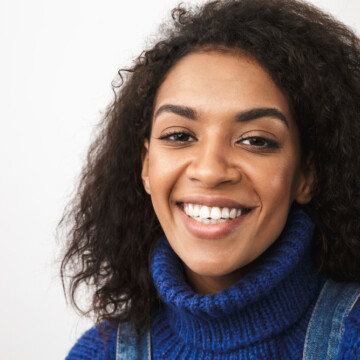 African American woman with frizzy hair and split-ends on 3C natural curls wearing a blue sweater.