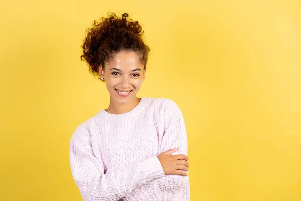 Happy American woman wearing a curly ponytail with her edges styled with baby oil and petroleum jelly.