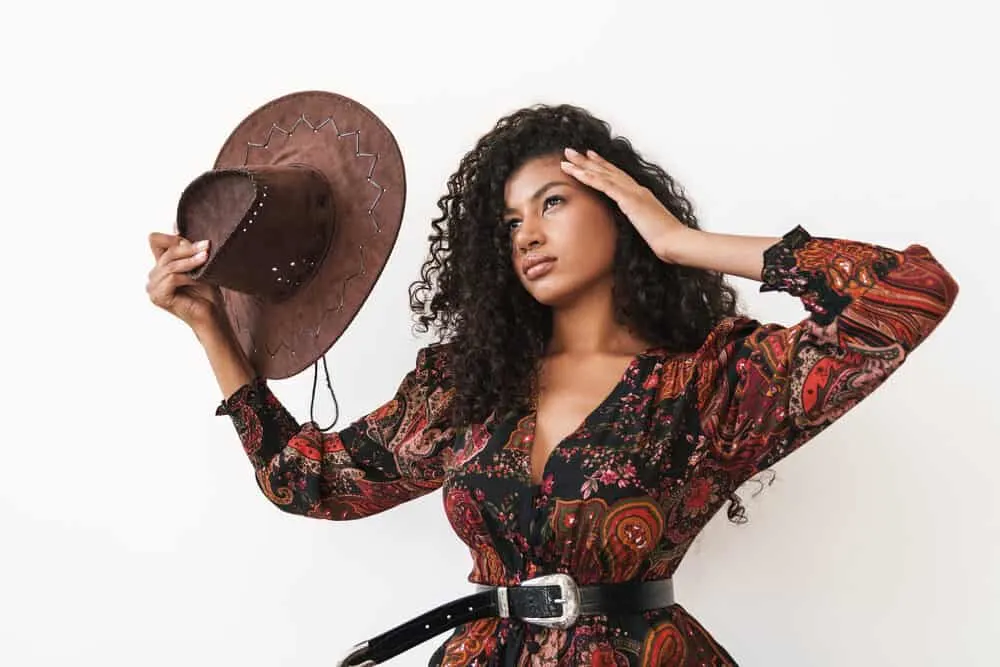 A beautiful young woman with 3B curls dressed like a 1950s cowgirl from a western movie.