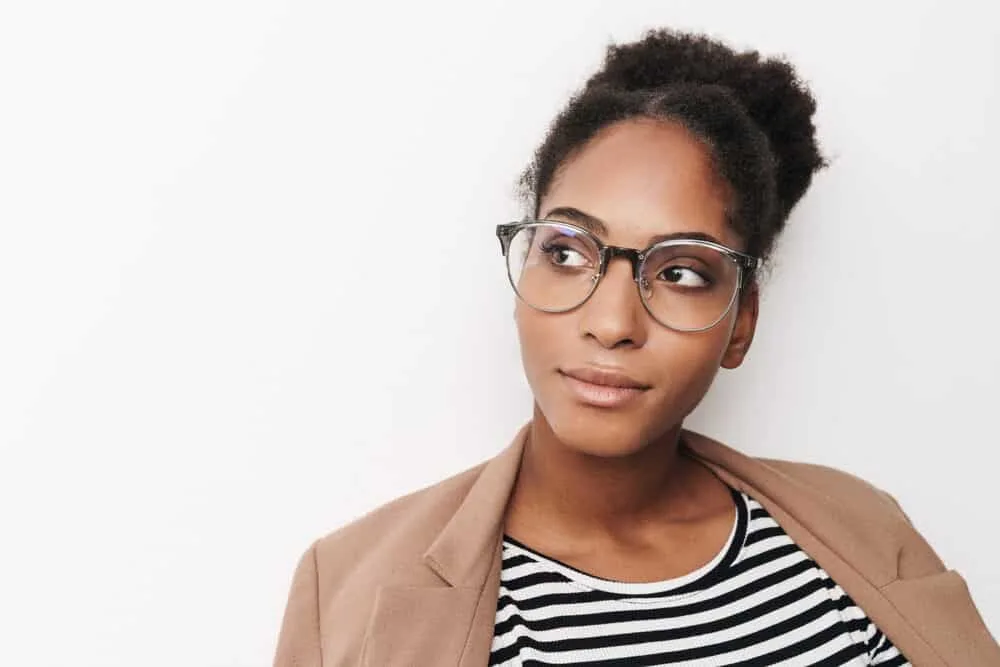 Beautiful black girl with black curly hair wearing a brown jacket and casual clothes.