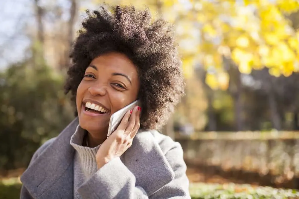 Lady with 4A curls moisturized with cold-pressed virgin coconut oil from fresh coconuts talking on the phone.