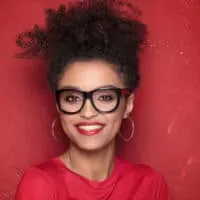 African American with a 3C curl pattern wearing red and black glasses with hoop earrings and red lipstick.