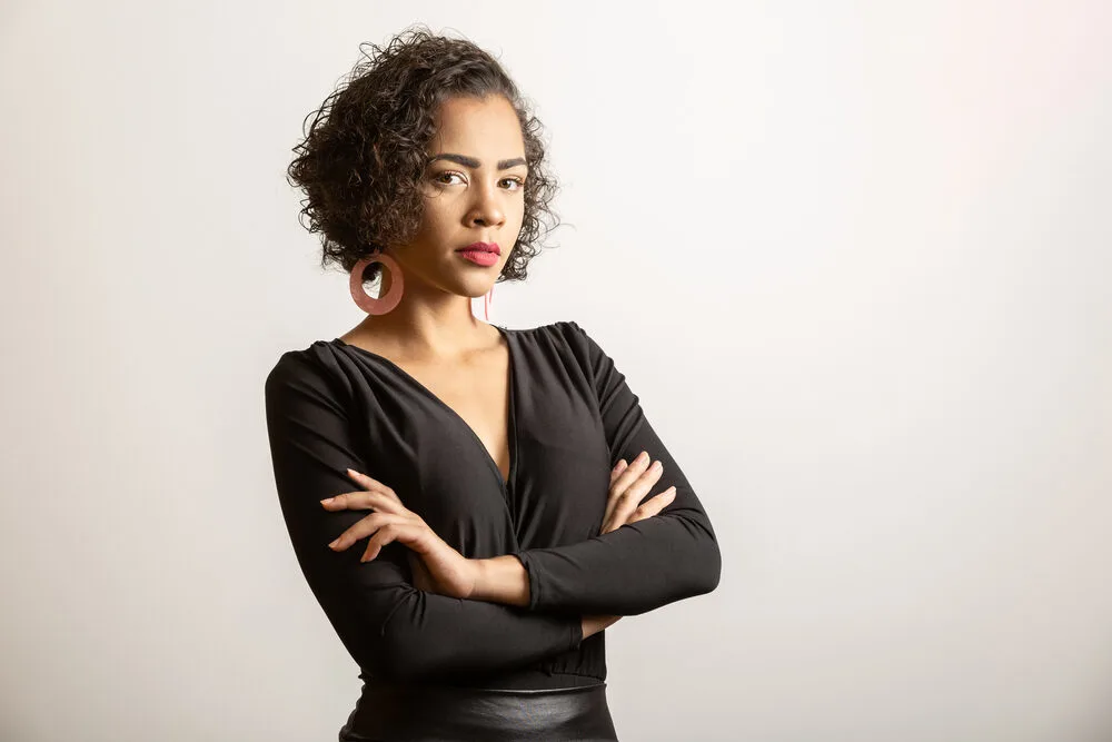 Confident professional female wearing 3B naturally curly hair with her arms folded.