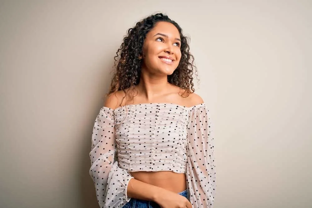 Young beautiful woman with curly hair wondering if she needs a regular haircut or just a trim.