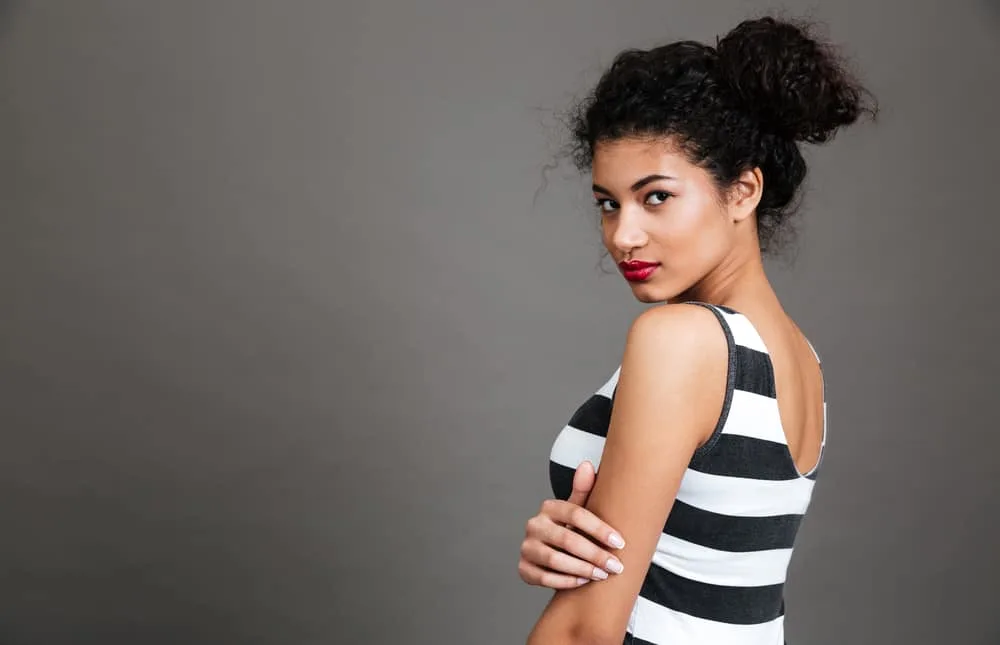 African American female with curly hair follicles styled with castor oil to encourage healthy hair growth.