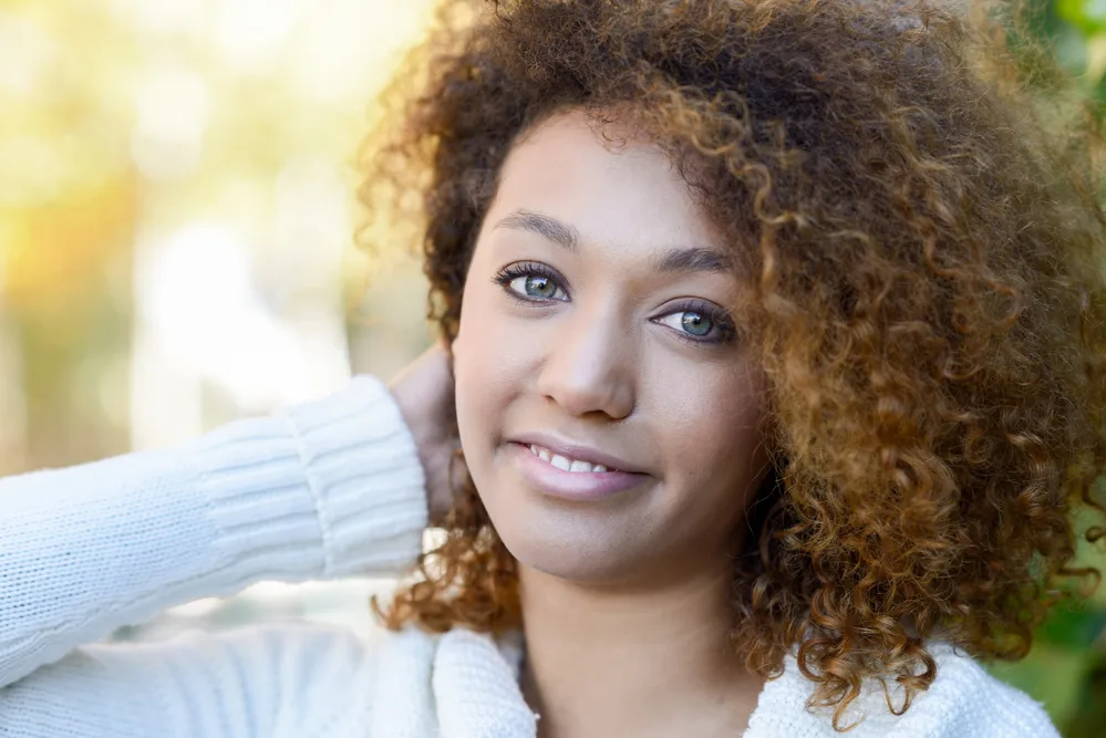 A beautiful black woman with a dark brown natural hair color has hot roots from using dark dye on her virgin hair.