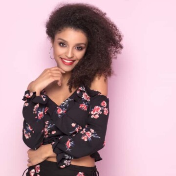 Beautiful African American female with a curly hair structure posing after getting hair lightening services.