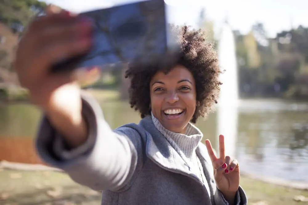 A woman with a great smile and naturally curly twist-out hairdo created virgin coconut oil from fresh coconut meat. 