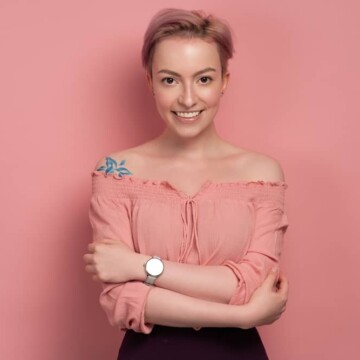 Cute white girl wearing a pink blouse with a short hairstyle created with a medium wave brush and pink hair dye.