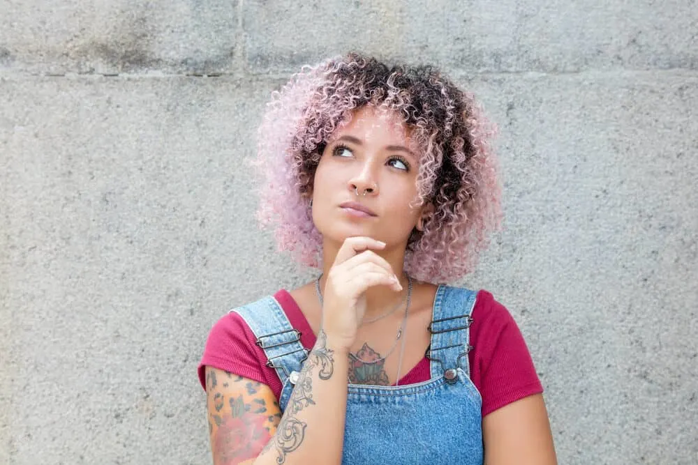 A cute black woman with brown and pink colored hair that has been dyed with natural hair dye.