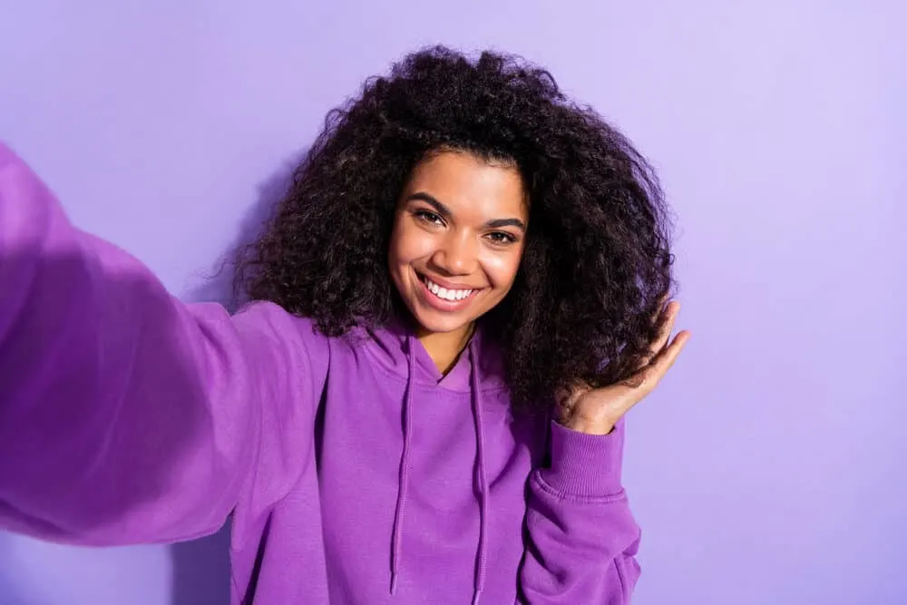 Charming black girl with significantly less hair loss after treating dandruff with an anti-dandruff shampoo.