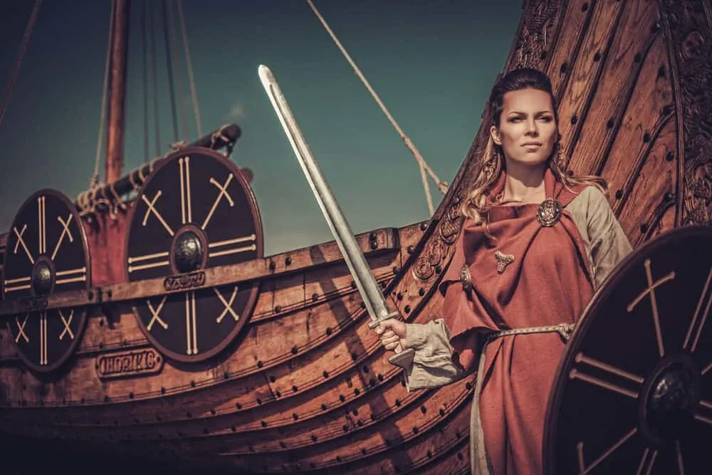 Woman wearing Viking dreadlocks carrying a sword and shield as she prepares for a battle.