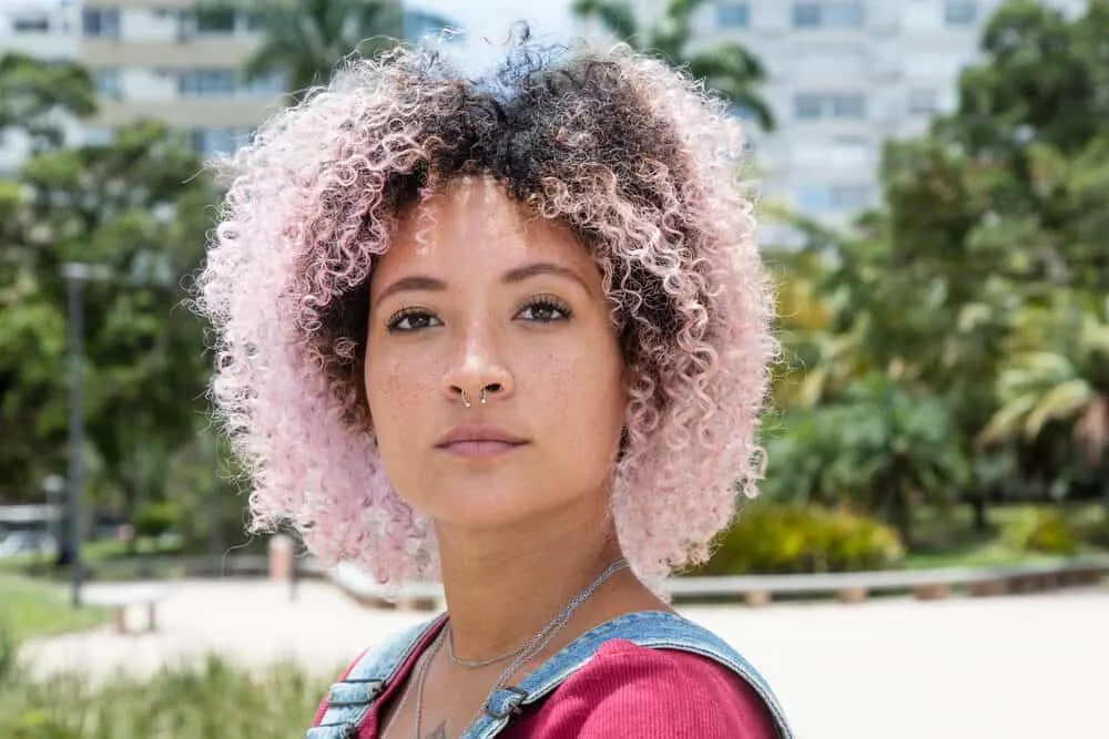 African American female with naturally brown hair with pink tips that's been styled with natural oils in a wash n go.