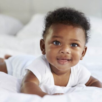 Cute baby girl born with hair during the fetal development process and peach fuzz on her arms, back, and legs.