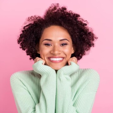 Cute African American female with caramel skin that uses biotin supplements to promote hair growth.