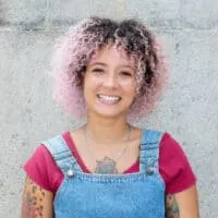 Cute African American female with dark brown natural hair wearing pink temporary hair dye on her 3C curls.