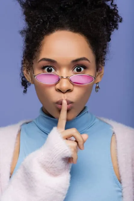 Adult with curly hair strands wearing pink shades and casual clothes.