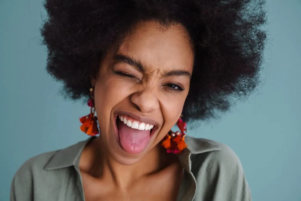 African American girl with natural black hair is sticking her tongue out making a funny face.