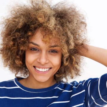 Cute young African American female with dark brown hair with highlights styled with natural oils.