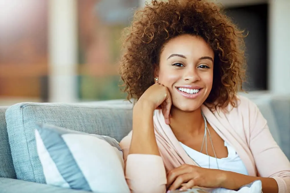 A black girl with dark brown hair wearing casual weekend clothes with a silver necklace and diamonds earrings.