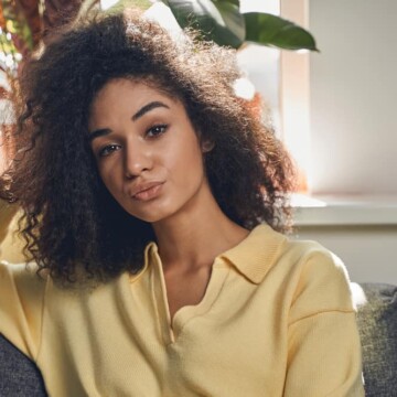 Beautiful African American female whose brittle hair feels like straw after an inadequate hair care routine.