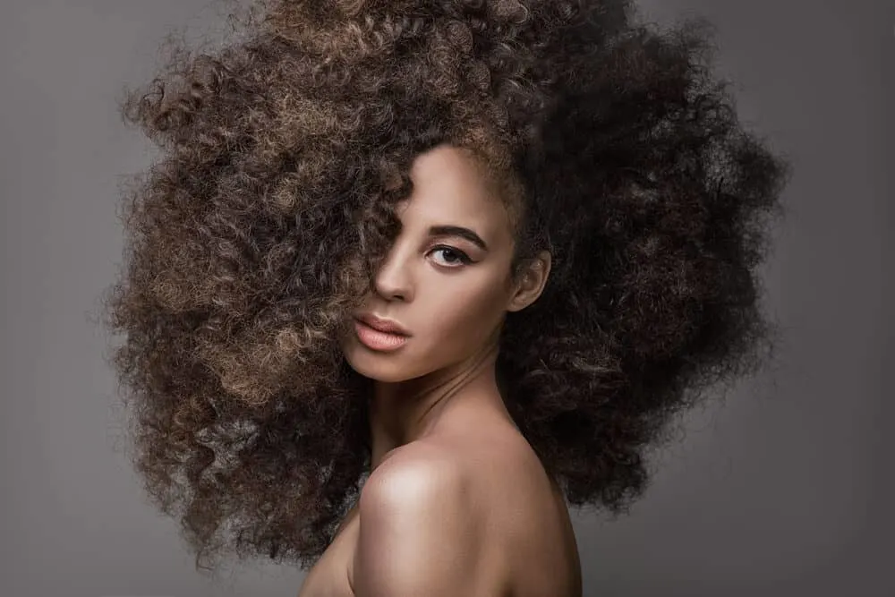 African women wearing a brand new synthetic wig that's been styled with a wig comb.