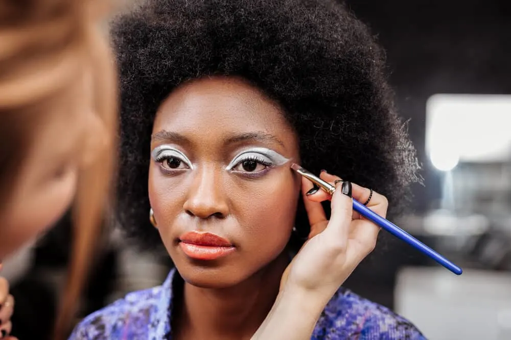 Cute African American with a kinky fro styled with olive oil after sitting under a hooded dryer.