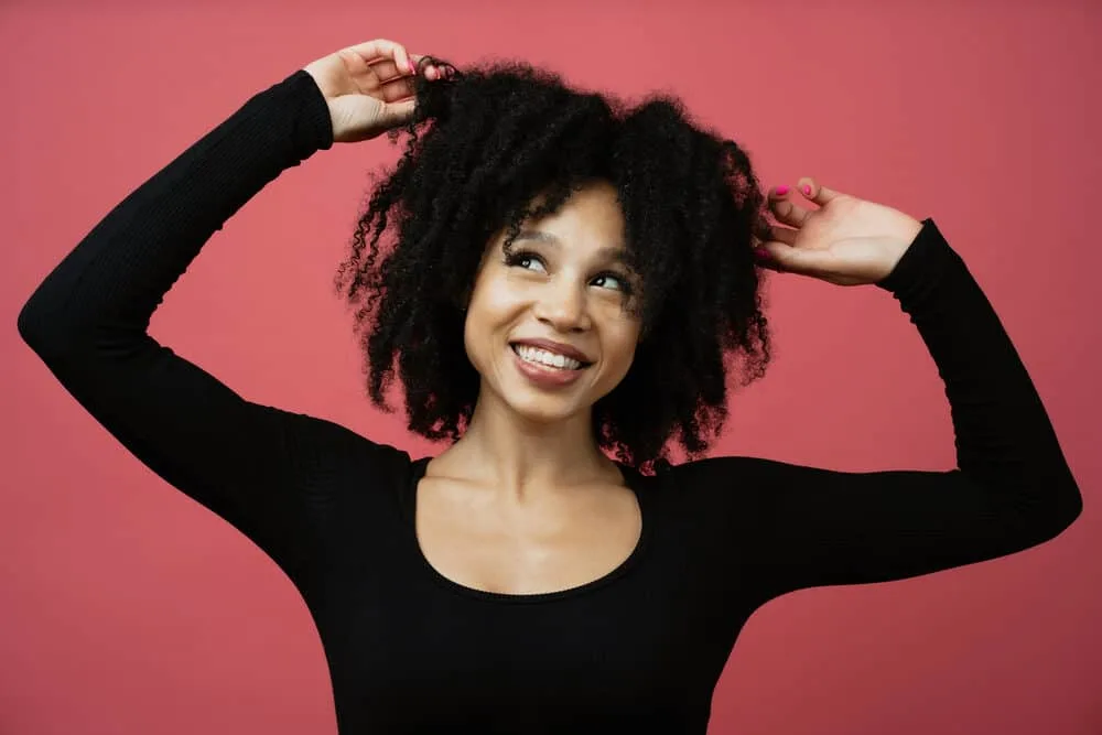 Cute African American girl looking away while rubbing her fingers through her kinky, curly 4A hair follicles.