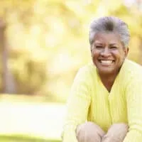 Mature African American female with mostly grey hair with a few dark hairs in the middle wearing a yellow sweater.