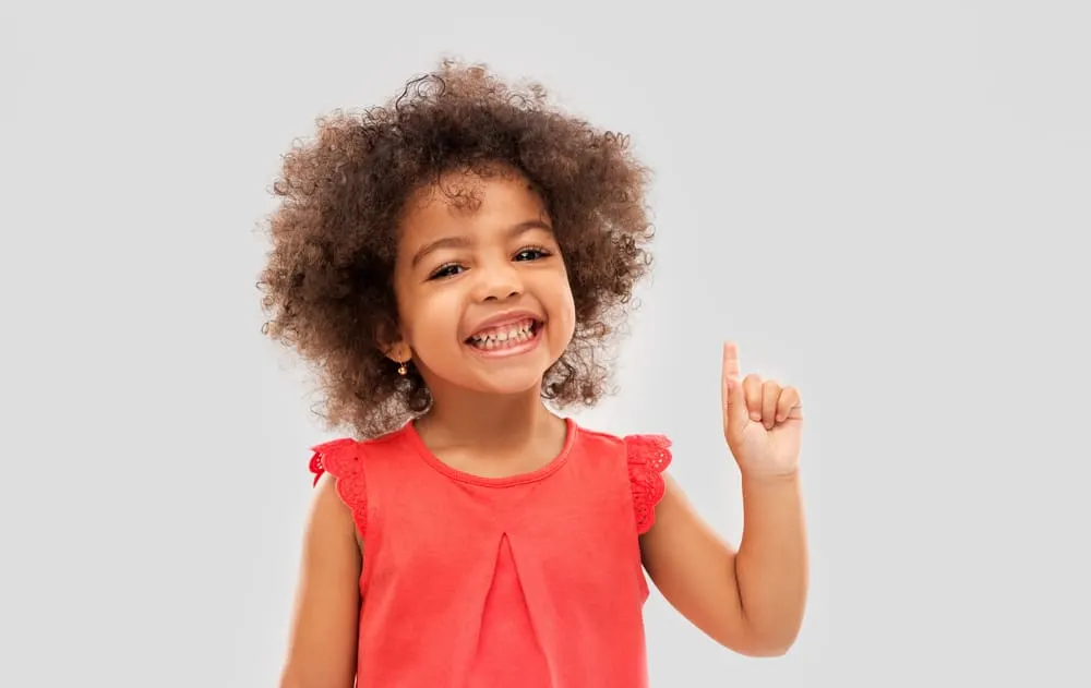 Adorable mixed-race baby with a big smile holding up one finger.