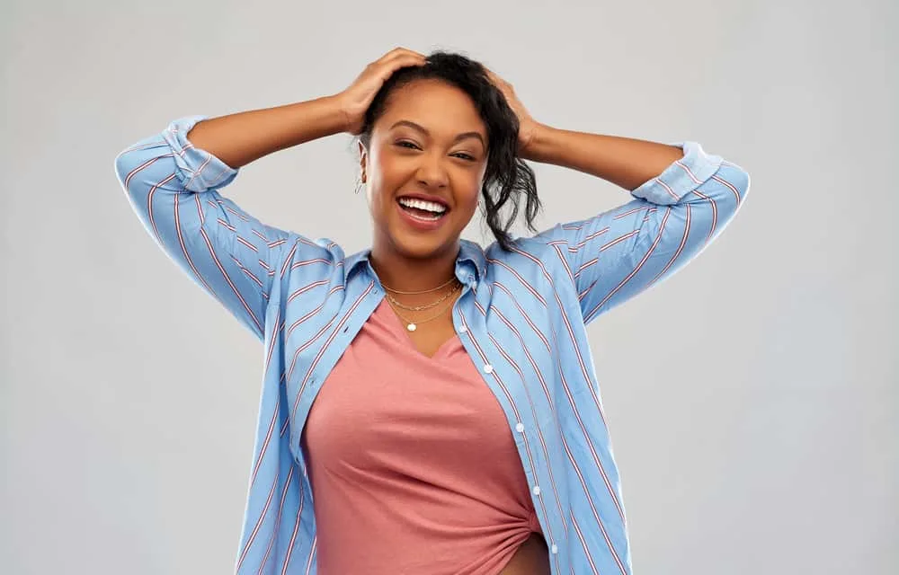 Cute African American female after using a dry hair straightener at high temperatures on her natural curls.