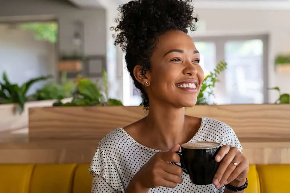 Black lady with natural curls that keeps her hair soft with massaging her scalp with natural sebum.