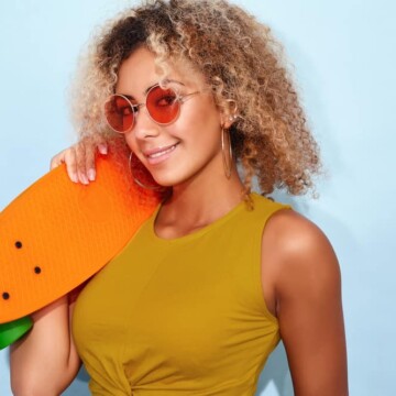 Cute African American female with dark brown hair with orange tones wearing rose-colored glasses.