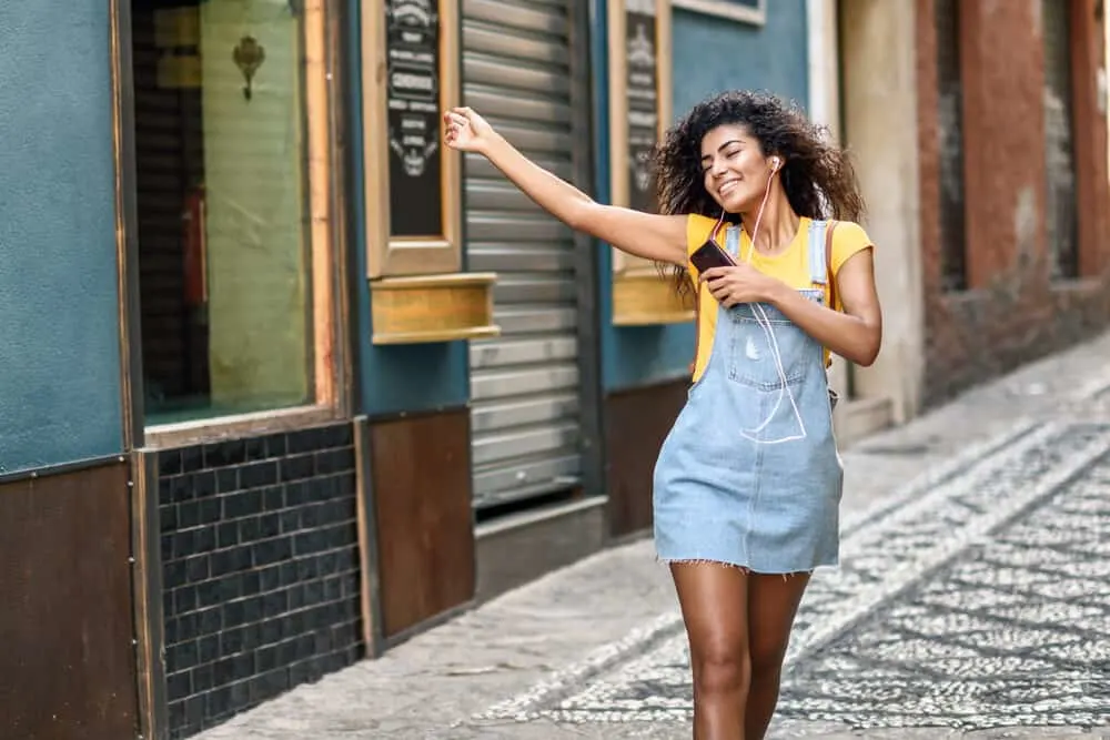 African female listening to music with straight textured hair follicles styled with coconut oil and a soft brush.