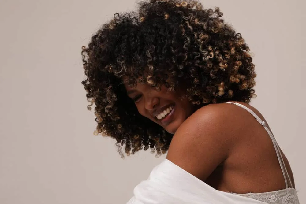 Joyful young woman planning to dye freshly washed hair with a blonde and brown color treatment.